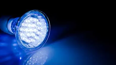 Close-up of an LED bulb glowing bright blue against a black background.