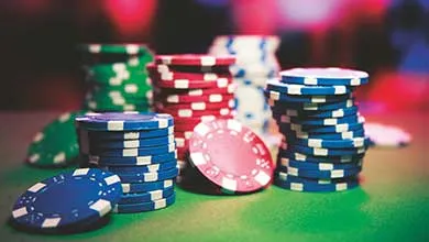 Stacks of blue, red, green, and white poker chips on a green felt table, with some chips scattered in front.